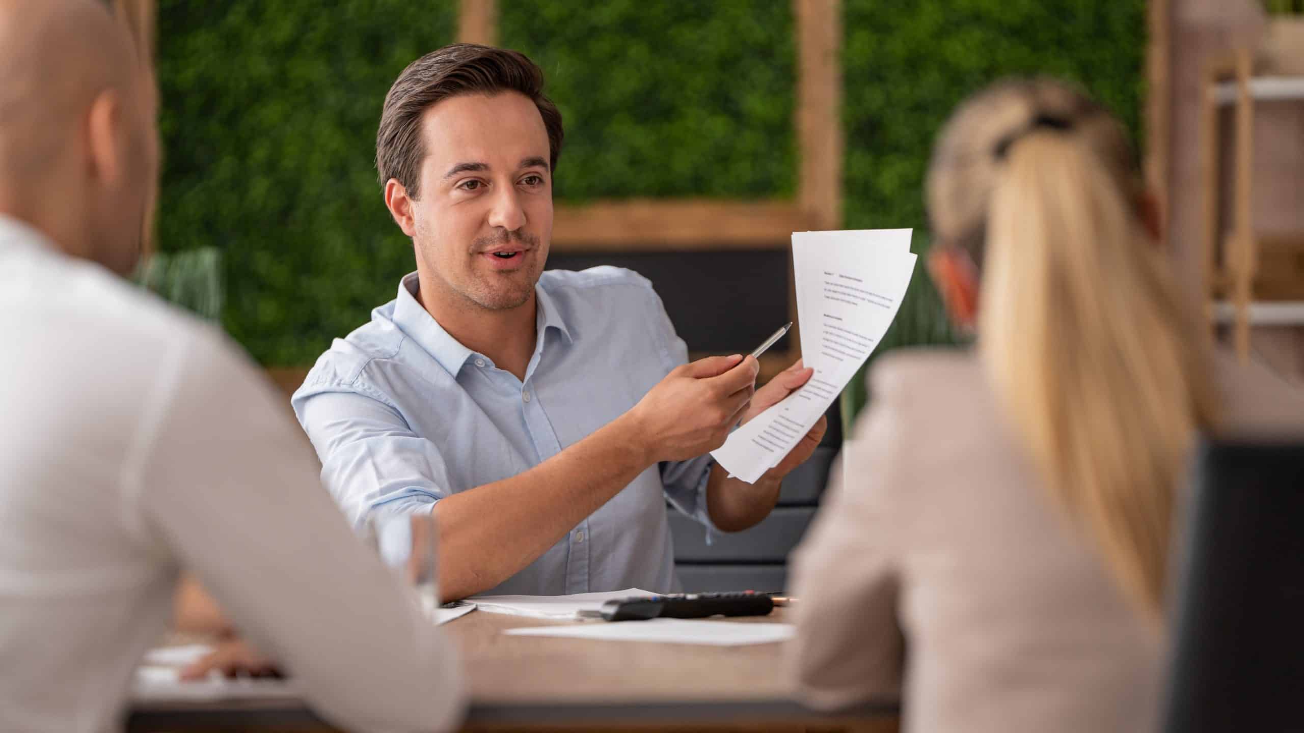 A man attentively holds a document during a business meeting around a table